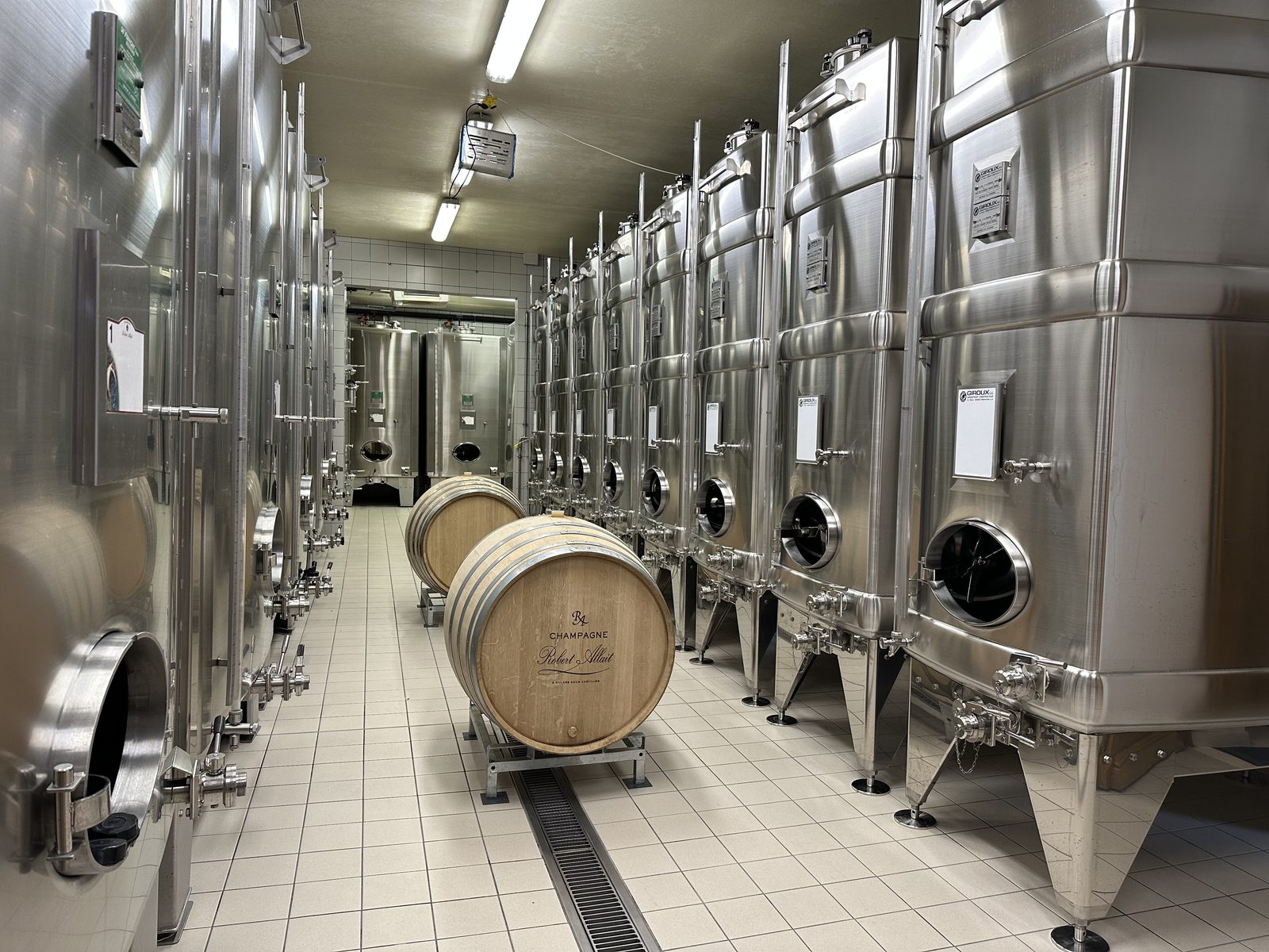 Robert-Allait cellar: two oak barrels branded with the house name among rows of stainless-steel tanks